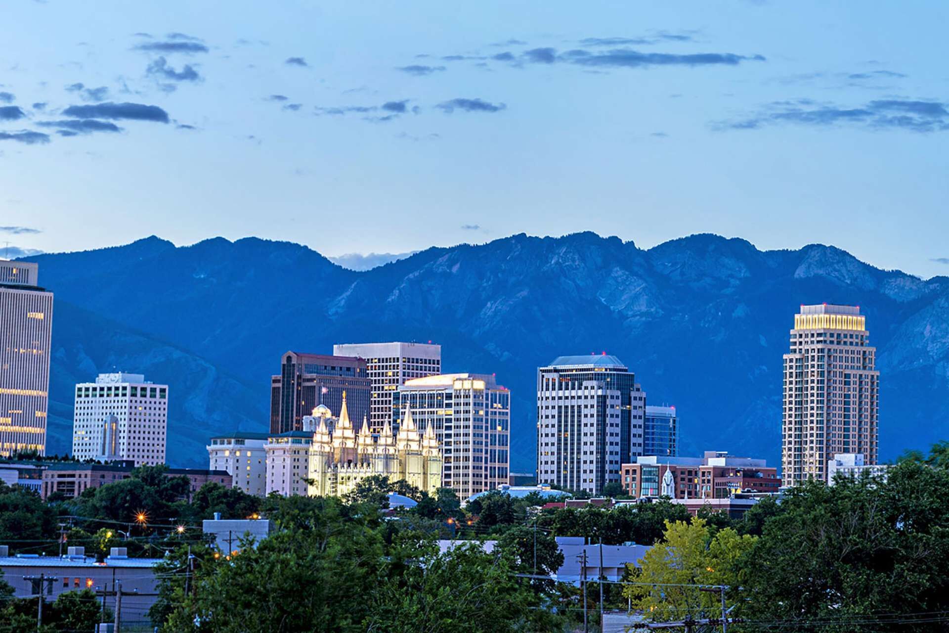 A cityscape with a prominent cathedral and modern buildings, set against a mountain backdrop.