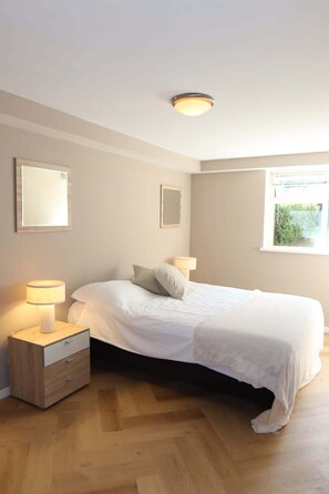 Ein Schlafzimmer mit Bett, Nachttischlampen, einem Schminktisch und einem Fenster.