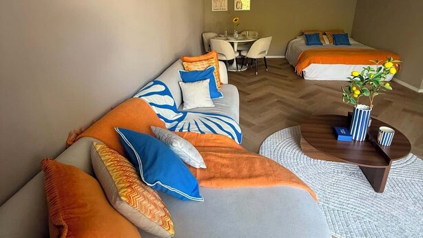 Un saló modern amb un sofà corbat, una taula de centre rodona i una zona de menjador amb taula i cadires.