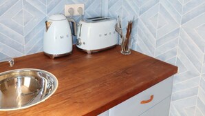 Cuina amb taulell de fusta, dos torradors blancs, un rentaplat de coure inoxidable i un salvassecs amb dibuixos blaus.