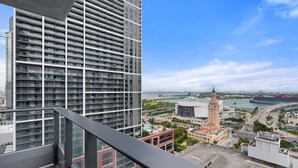 A high-rise building with a view of a cityscape, including a prominent tower and a stadium. - Signature Cityview Two-Bedroom Miami 501 First #2512 (Miami)