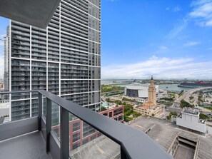Ein Hochhaus mit Blick auf eine Skyline, darunter ein markanter Turm und ein Stadion.