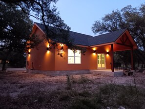 A house with a sloped roof, large windows, and a covered porch. - Delightful 1-bedroom cottage with AC in Dripping Springs (Dripping Springs)