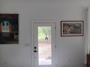 Een kamer met een witte deur, een schilderij aan de muur en een lijst met een afbeelding.