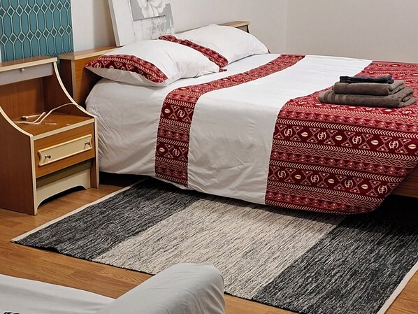 A neatly arranged bedroom with a bed, bedside table, and a rug. - International Business (Pau)