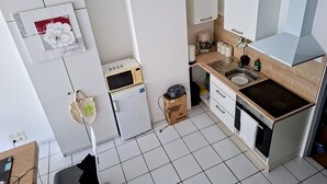 A compact kitchen with a microwave, coffee maker, and a sink. - International Business (Pau)
