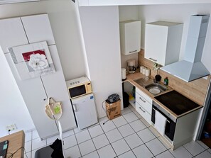 A compact kitchen with a microwave, coffee maker, and a sink. - International Business (Pau)
