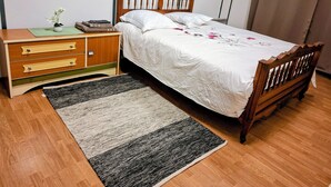 A bedroom with a wooden bed, a nightstand, a dresser, and a window with blinds. - International Business (Pau)
