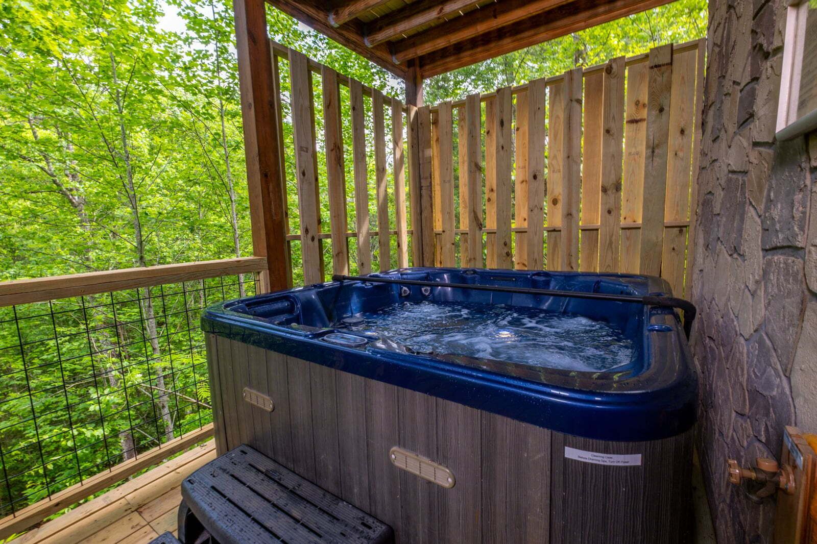 A hot tub in a wooden deck with a view of a forest.