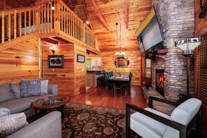 A wooden cabin interior with a dining area, fireplace, and a staircase leading to an upper level. - Black Beary Lodge・Hot Tub・Pool Table・Community Pool・Arcade (Gatlinburg)