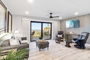 A modern living room with a sofa, armchairs, a coffee table, and a TV mounted on the wall. - Direct Oceanfront Condo | Balcony, Heated Pool + Putting Green 🍹🏝️ (Cocoa Beach)