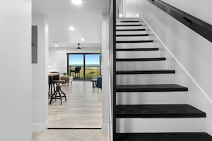 A staircase with black steps leading to a balcony with a view of the ocean. - Direct Oceanfront Condo | Balcony, Heated Pool + Putting Green 🍹🏝️ (Cocoa Beach)