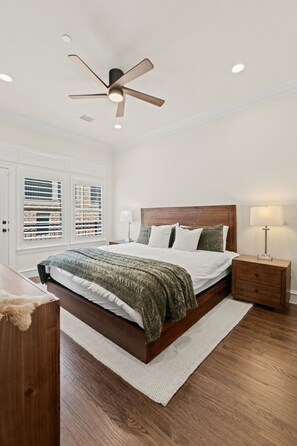 A bedroom with a bed, nightstand, lamp, ceiling fan, and window blinds. - Executive Townhome in Legacy District Plano & Frisco Welcoming FIFA Guests! (Plano)
