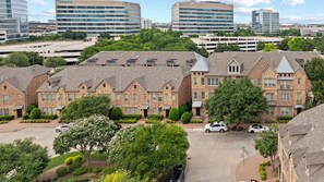 A residential area with brick houses, a parking lot, and modern office buildings in the background. - Executive Townhome in Legacy District Plano & Frisco Welcoming FIFA Guests! (Plano)