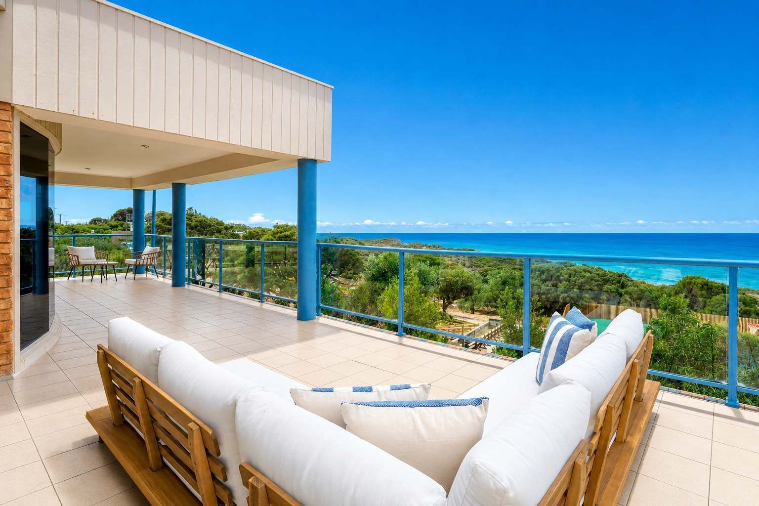 Un balcon avec vue sur la mer, des meubles en bois et un ciel dégagé.