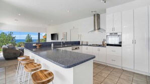 Een moderne keuken met een groot eiland, witte kastjes en uitzicht op de omgeving.