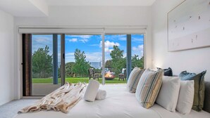Een slaapkamer met een grote schuifpui naar een balkon met een vuurkuil en buitenmeubilair.