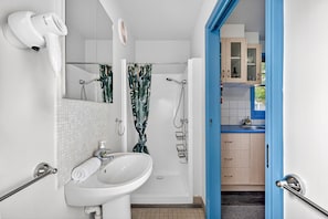 Een moderne badkamer met een douche, wastafel en haardroger.
