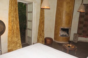 Ein Zimmer mit einem Bett, Kamin, Vorhängen und Pendelleuchten.