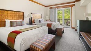 Ein Hotelzimmer mit zwei Betten, einer Bank, einem Schreibtisch und Blick ins Freie.