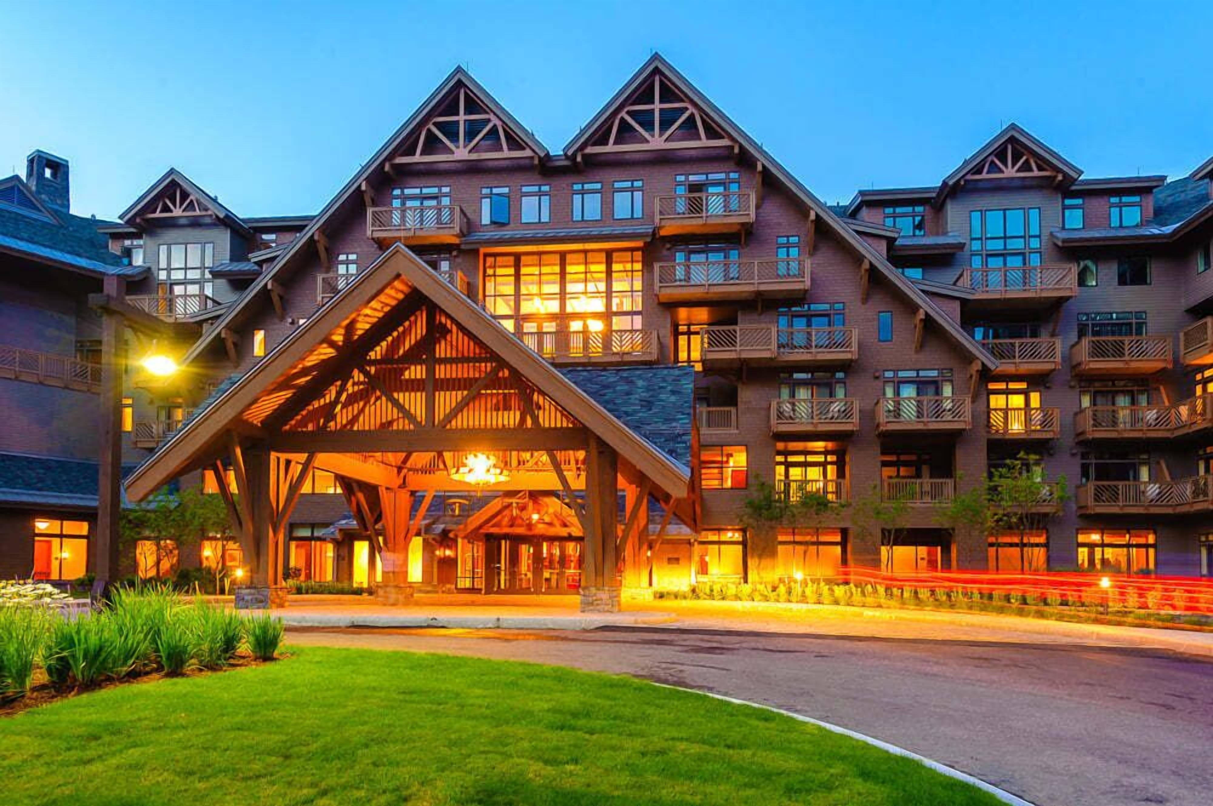 Un hotel de varios pisos con una entrada de madera llamativa y balcones.