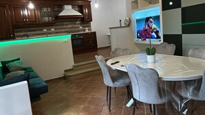 Een moderne woonkamer met een eethoek, keuken en een aan de muur bevestigde televisie.