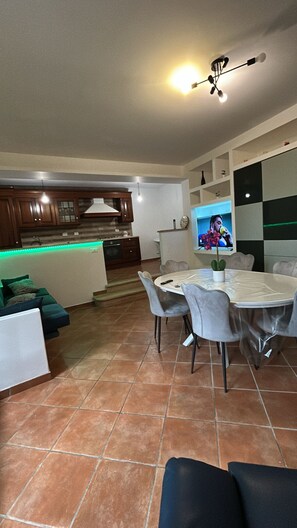 Un soggiorno moderno con zona pranzo, cucina e televisore a parete.