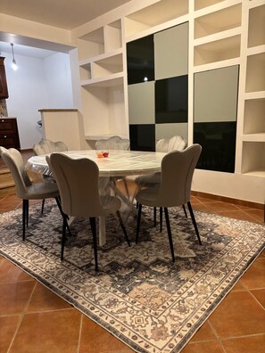 A dining area with a round table, six chairs, and a patterned rug. - Vrbo Property (Castel Gandolfo)