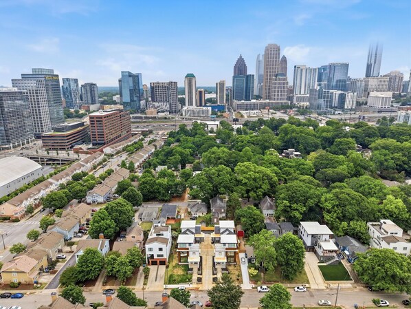 Ett bostadsområde med en blandning av moderna och äldre byggnader, omgivet av täta, grönskande träd.