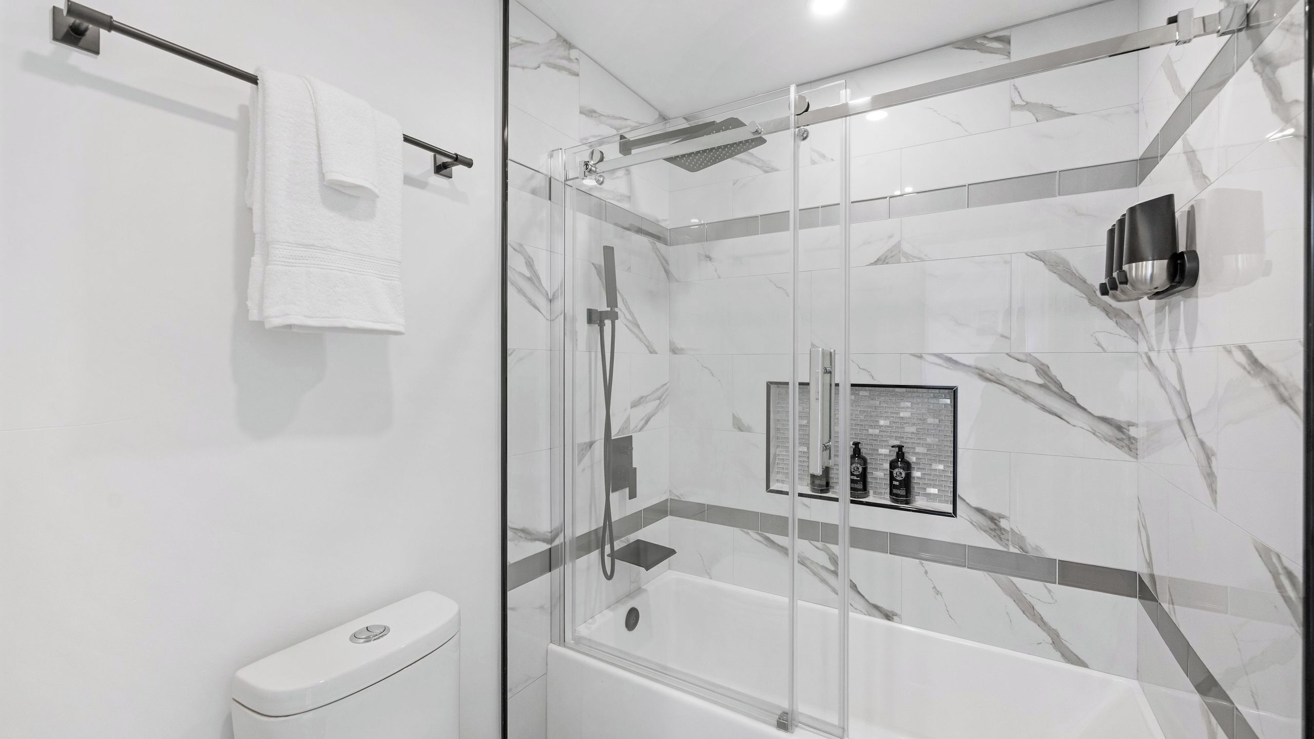 A modern bathroom with a glass-enclosed shower, a glass-enclosed bathtub, and a toilet.