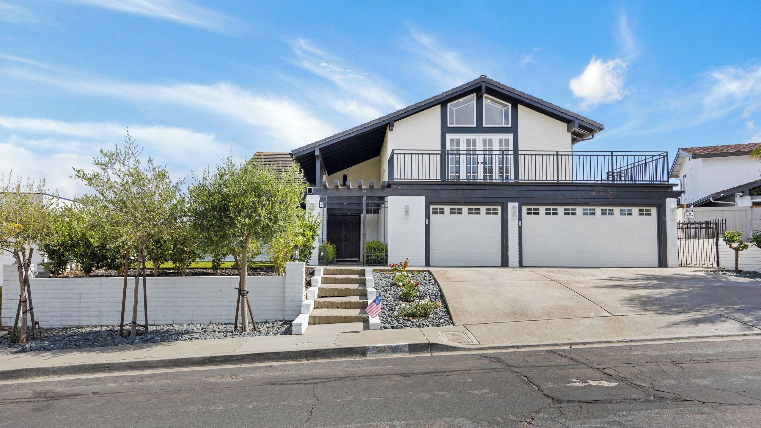 A two-story residential building with a balcony, a garage, and a small front garden.