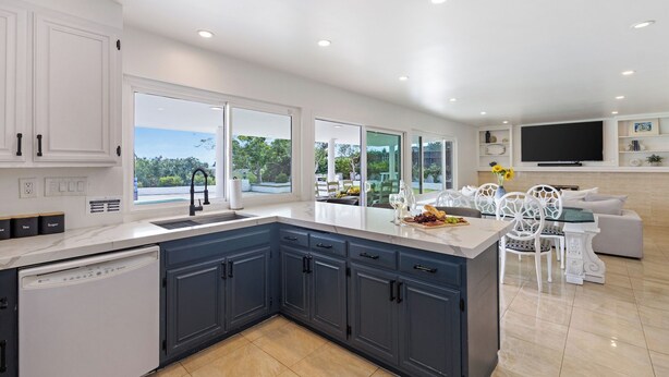 A modern kitchen with a large island, white cabinetry, and a view of the outdoors. - Skyline Palms by Avantstay Pool + 2 Hot Tubs + Outdoor Dining Near La Jolla + Pacific Beach (San Diego)