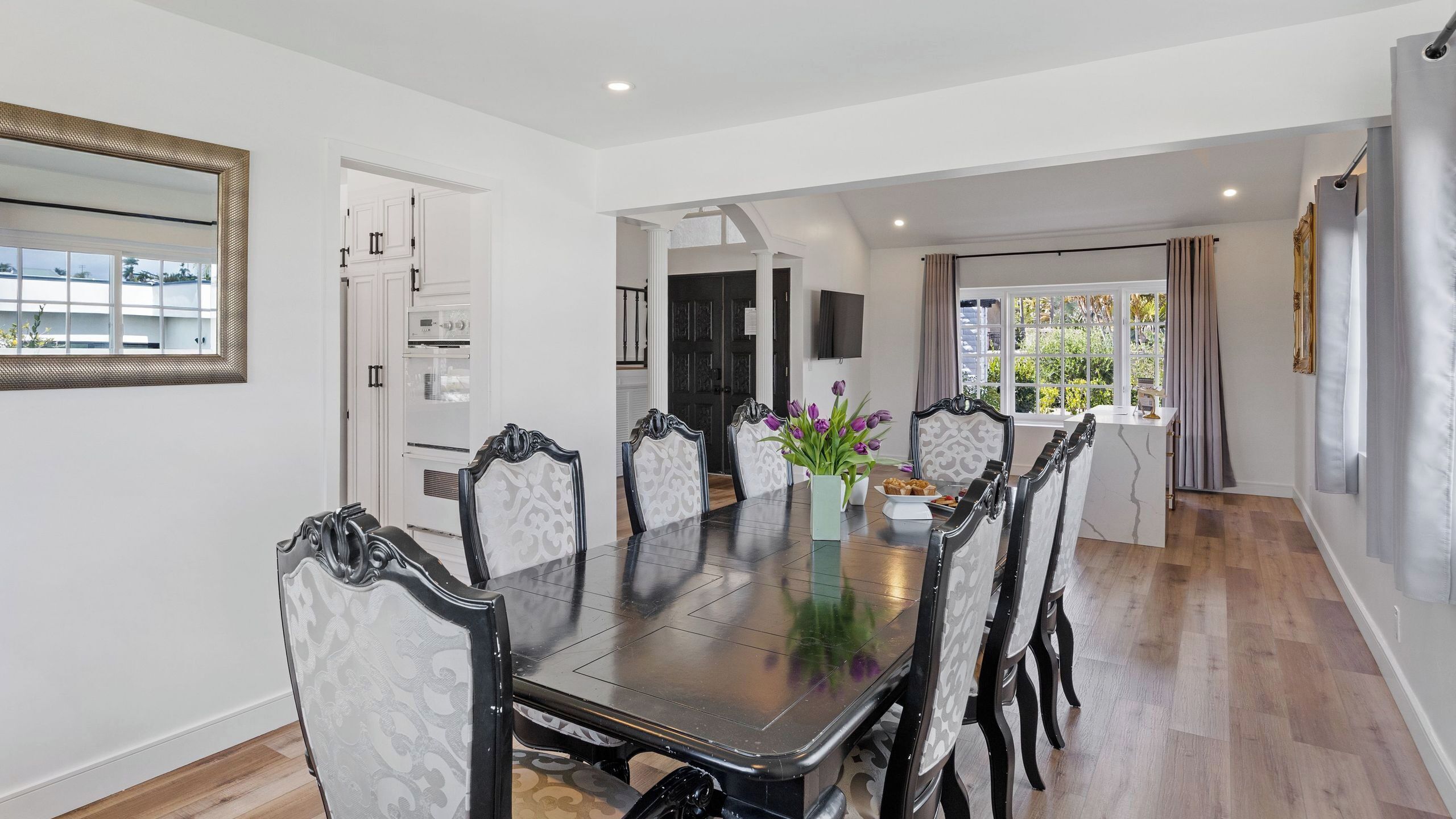Une salle à manger avec une grande table, des chaises et un vase de fleurs.