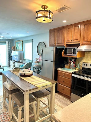 A kitchen with wooden cabinets, a stainless steel refrigerator, a microwave, and an oven. - 2BR Holden Beach condo with pool and pet-friendly. (Holden Beach)