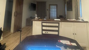 Een eetgedeelte met een tafel, stoelen, een plafondventilator en een keuken op de achtergrond.