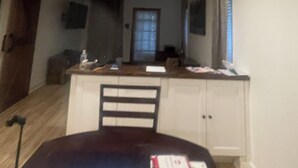 Un espace repas avec une table, des chaises, un ventilateur de plafond et une cuisine en arrière-plan.