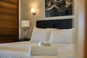 A hotel room with a bed, a nightstand with a lamp, and a wall-mounted light fixture. - Harbour Views Morning Sun on Iconic Princes Wharf (Auckland City)