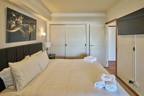 Et hotelværelse med en stor seng, et natbord med lampe, et billede på væggen og en garderobe med skydelåger.
