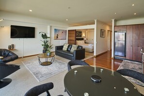 Ein modernes Wohnzimmer mit einer Couch, einem Couchtisch und einem an der Wand befestigten Fernseher.