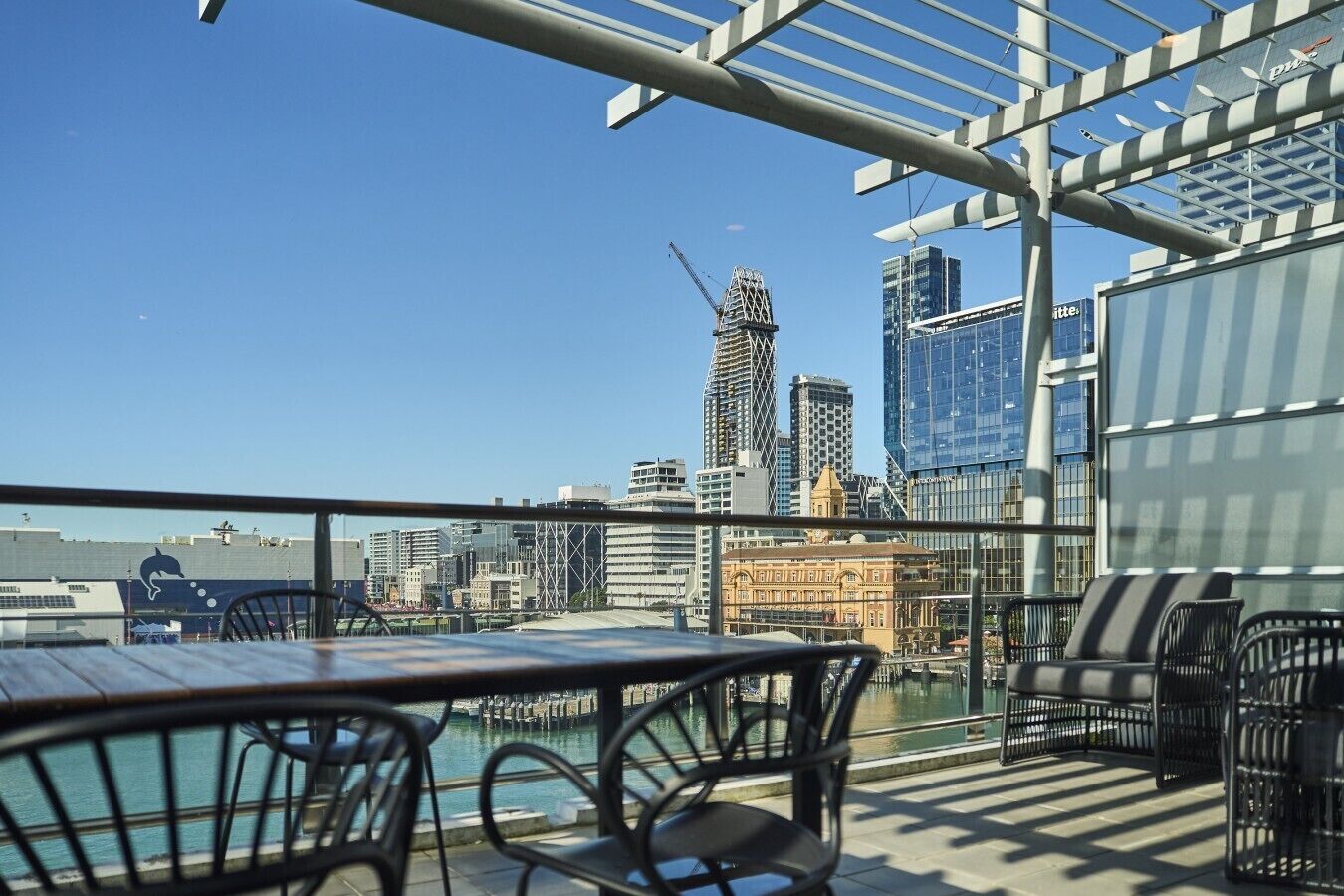 Une terrasse sur le toit offrant une vue sur les toits de la ville, avec notamment un bâtiment en construction qui se distingue.