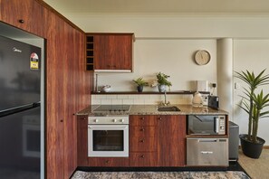 Eine Küche mit Kühlschrank, Herd, Backofen, Mikrowelle und Holzschränken.