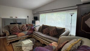 Een woonkamer met een hoekbank, een salontafel, een televisie en een lamp.
