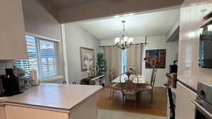 Een moderne keuken met een centraal eiland, een eettafel en stoelen, met een kroonluchter erboven.