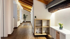 Een gang met houten vloeren, een schuin plafond en een ingebouwd schap met een plant.