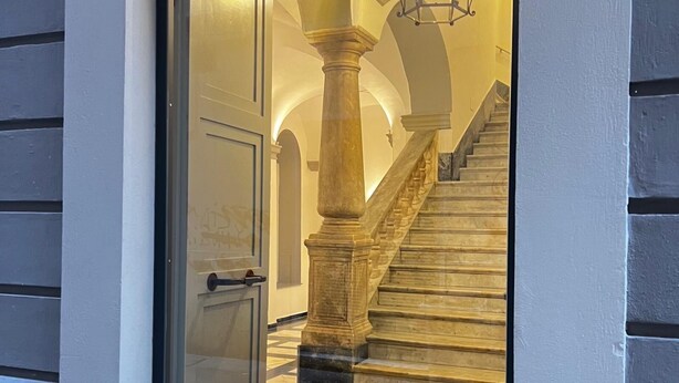 Een statige trap met marmeren treden en een houten balustrade, leidend naar een verdieping.