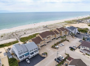 Ein Strandhotel mit mehreren Gebäuden, einem Parkplatz und Blick auf den Strand.