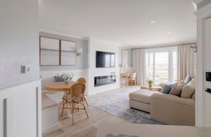 Een moderne woonkamer met een open haard, een eethoek en een bank.