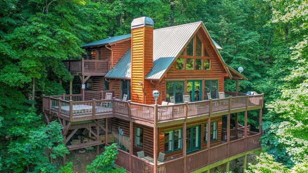 A log cabin with a balcony and a deck, surrounded by dense forest. - Bent Tree Cabin・Hot Tub・Game Room・Views + Scenic Binoculars (Jasper)