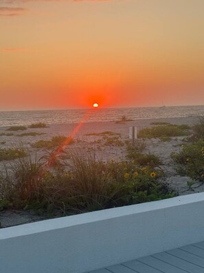 Ein Sonnenuntergang über einem Strand, ein Weg führt zum Wasser.