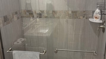Un espace douche doté d’une porte en verre, d’un porte-serviettes et d’un savonnière.